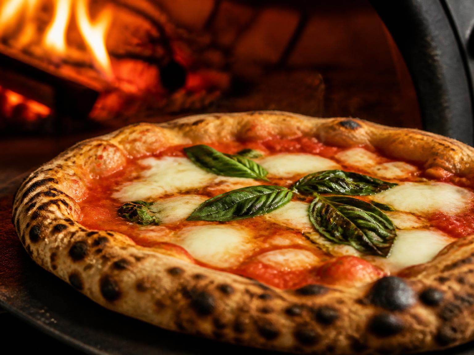 Pizza margherita met luchtige rand komt uit de steenoven